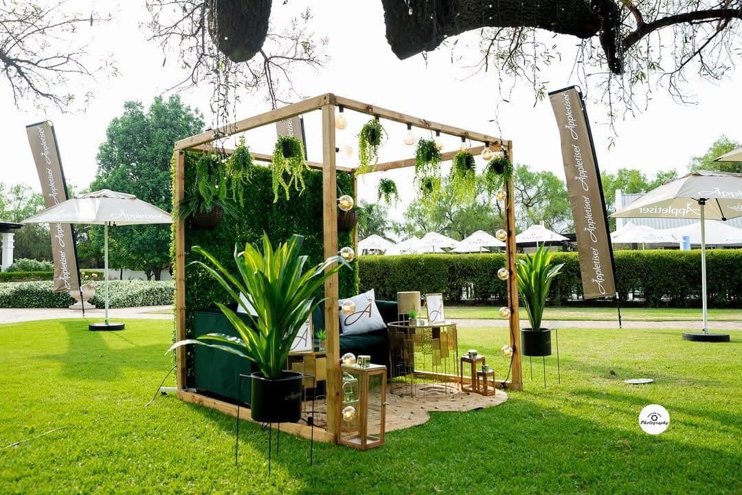Appletiser lounge: a timber pergola with hanging ferns, a velvet sofa and a green wall