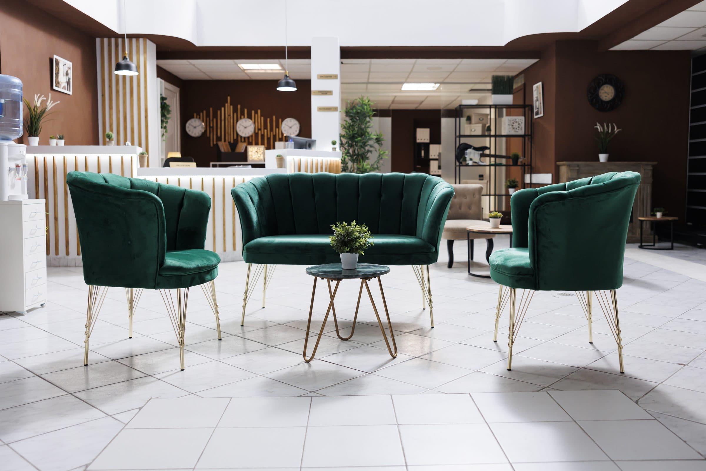 Emerald velvet tub chairs with brass legs arranged in a hotel lobby